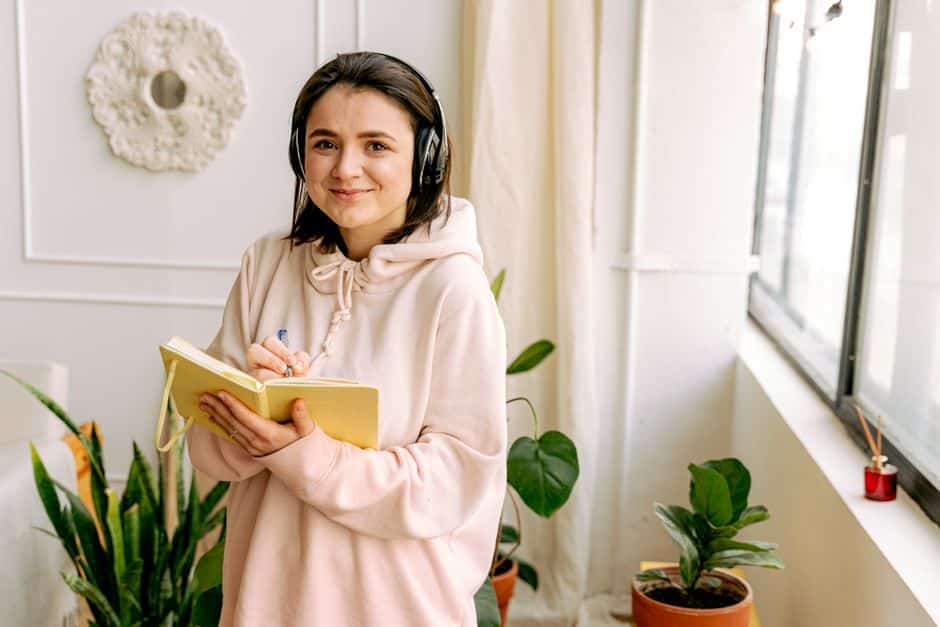 Jeune femme avec un casque audio prenant des notes dans un carnet